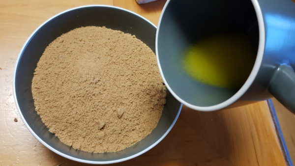 Mixing butter with biscuit crumbs for banoffee pie base