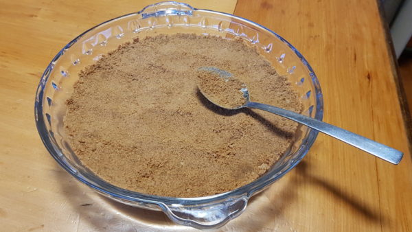 Pressing banoffee pie base into a glass pie dish