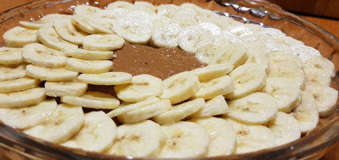 Bananas arranged on top of caramel layer of banoffee pie.